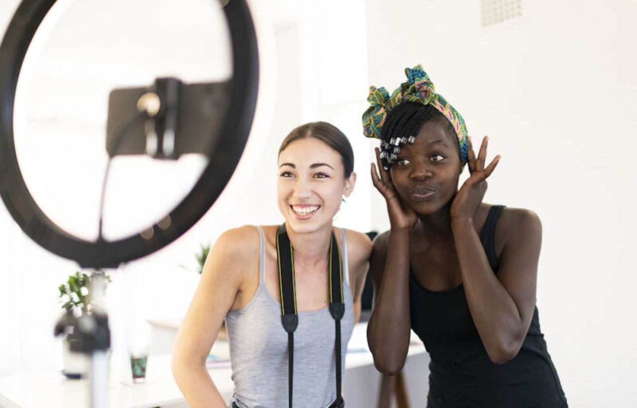 two women taking a video shoot and smiling to the camera designed with proper light
